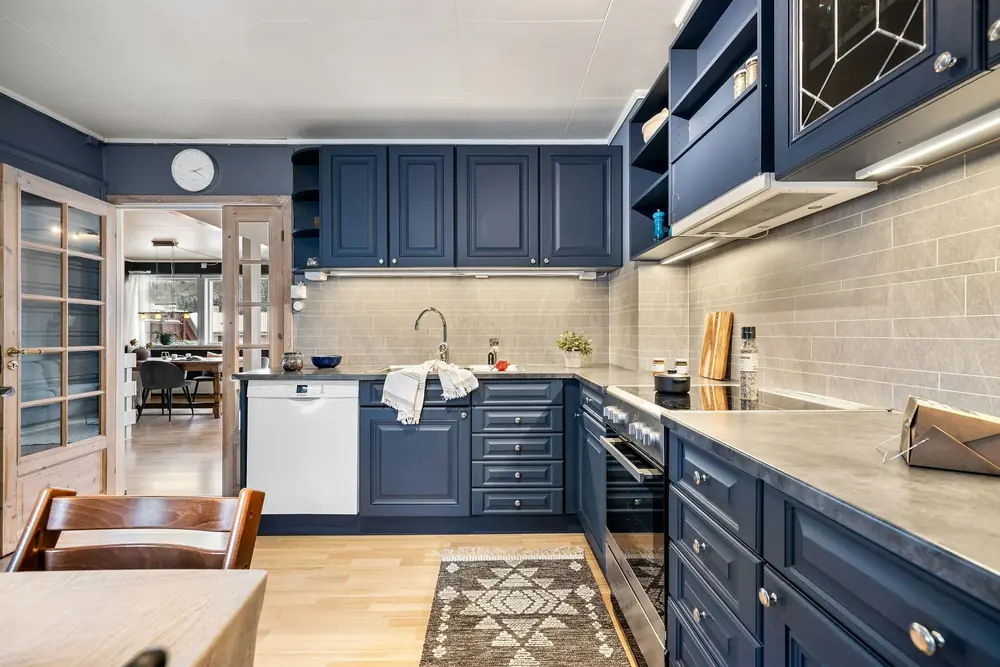Navy blue shaker kitchen cabinets with a gray subway tile backsplash and wood floors