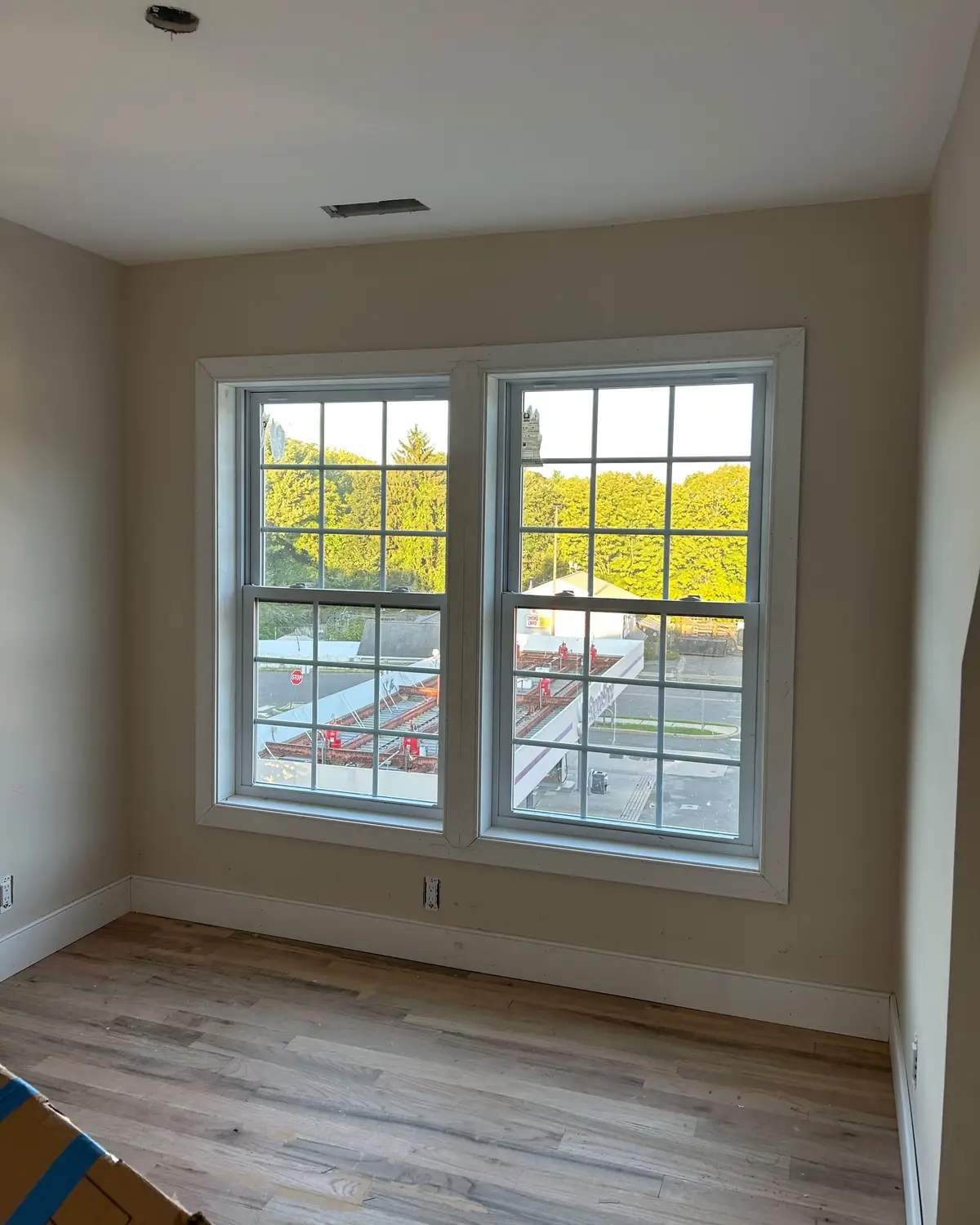 Bedroom with new wood look vinyl plank flooring, white baseboard and trimmed windows