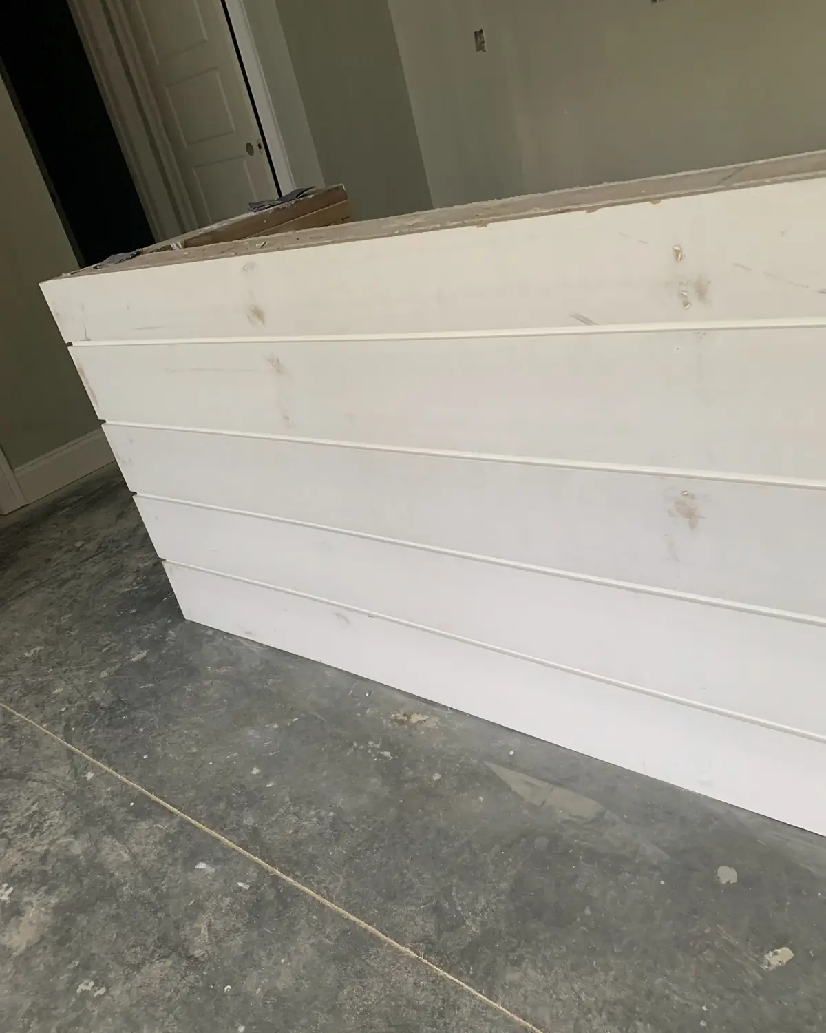 Kitchen island wrapped in white shiplap boards during a remodel