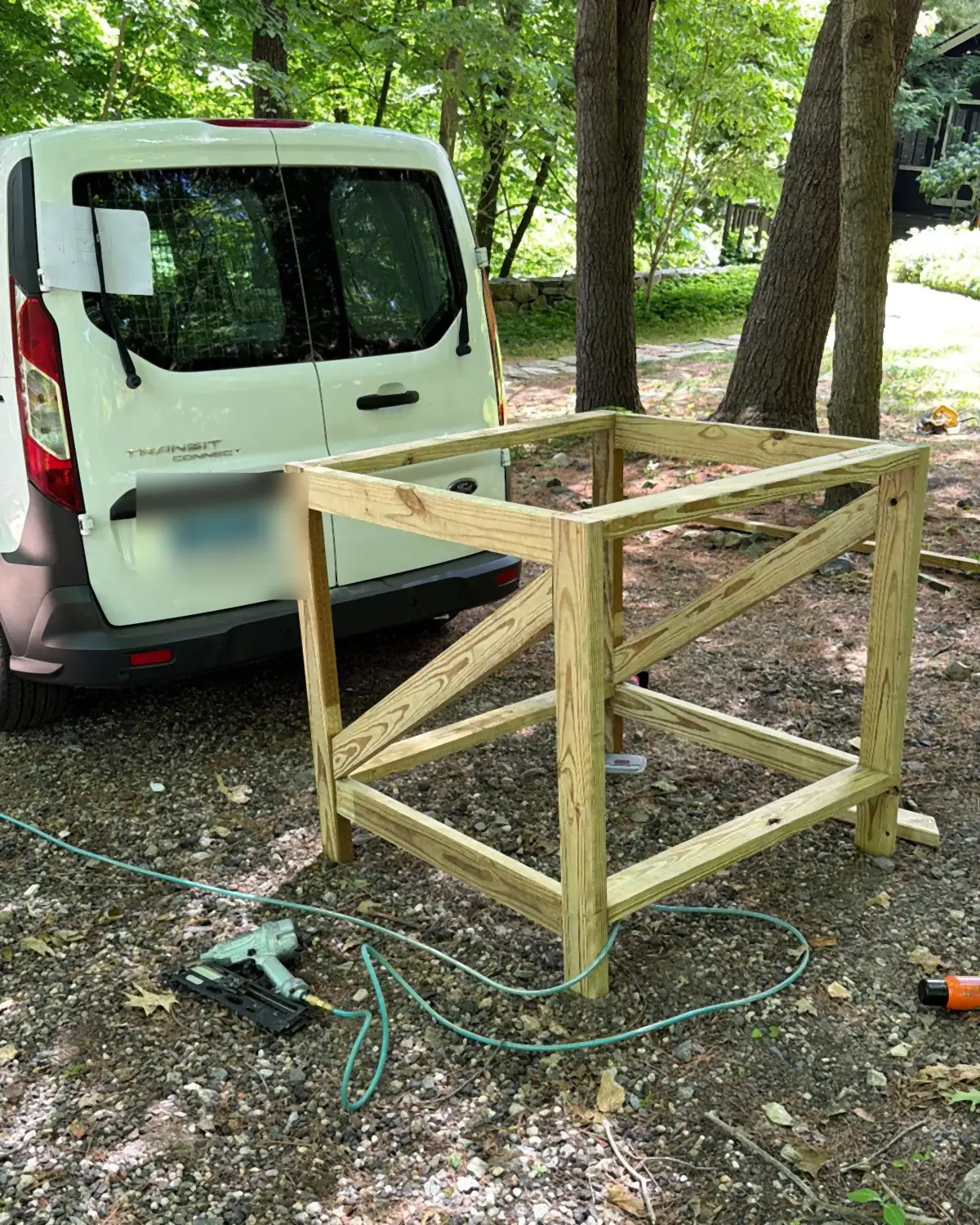 Work van parked at a job site next to a pressure treated lumber frame being built